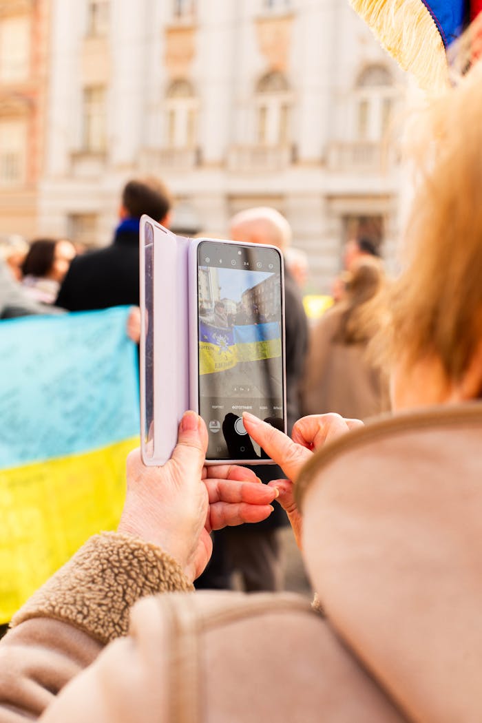 A person documenting a Ukrainian flag protest rally in Zagreb, Croatia, on their mobile phone.