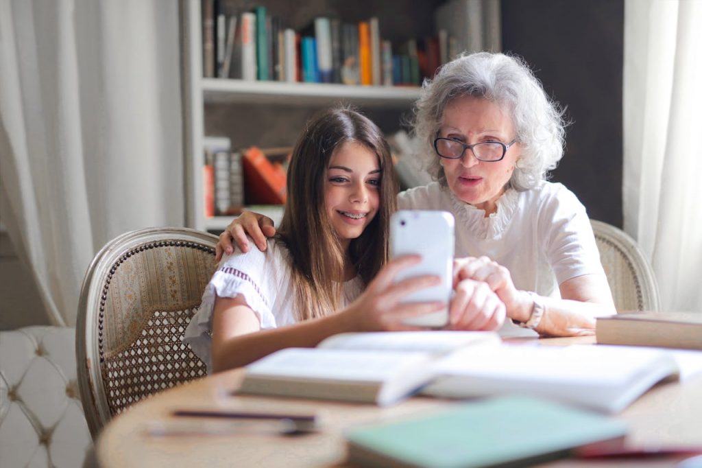 pexels photo 3768140 A grandmother and granddaughter bonding over a smartphone at home, showcasing generational connection.